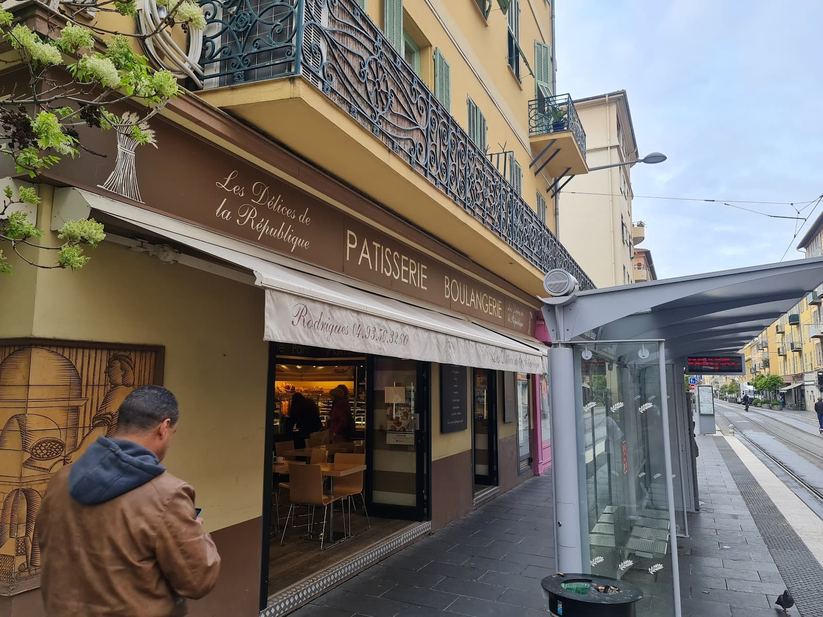 Devanture des Délices de la République, avenue de la République à Nice, avec l'enseigne Boulangerie Pâtisserie et l'arrêt de tram en premier plan
